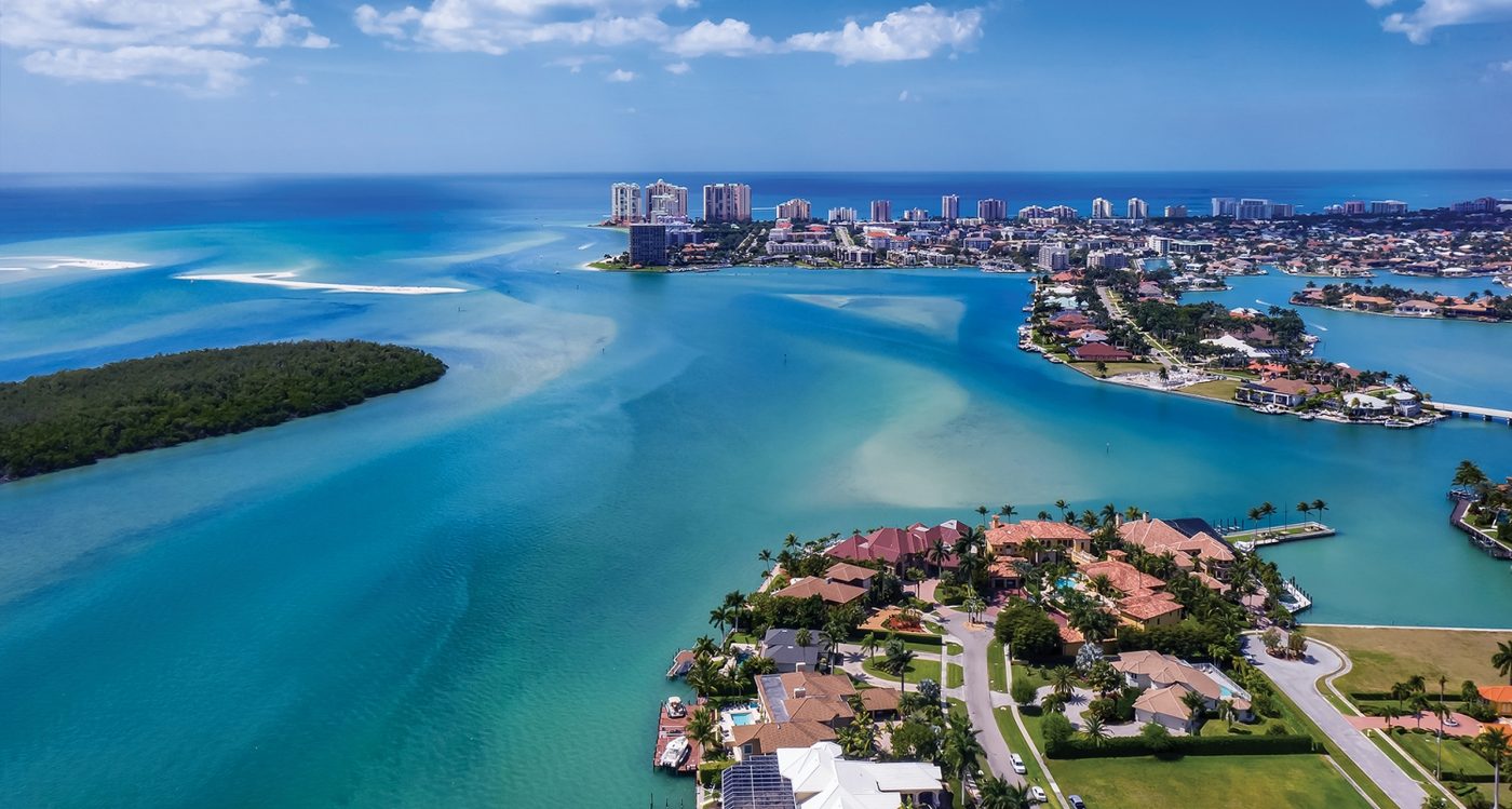 Aerial view of turquoise water, sandbars and mangrove islands beside waterfront homes and canals on Marco Island